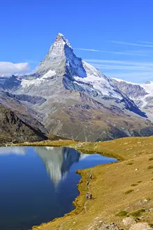 Hikers walking on the path beside the Stellisee with the Matterhorn reflected, Zermatt