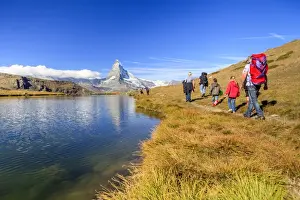 Walkers Prints: Hikers walking on the path beside the Stellisee with the Matterhorn reflected, Zermatt