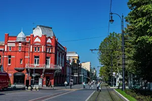 Center Prints: Historic architecture in Vladikavkaz showcases urban life on a sunny day with people walking in the city center of