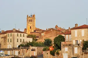 Glow Prints: Historic buildings and a clock tower are seen against the evening sky in a town in Gers department