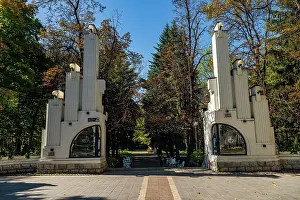 Columns Prints: Historic entrance to a park in Vladikavkaz with tall columns and trees in the background during a bright day