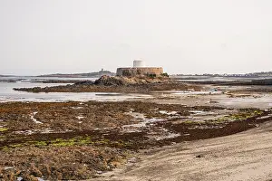Guernsey Prints: Historic Fort Grey Martello tower stands on tidal islet in Rocquaine Bay during low tide in Guernsey Channel Islands