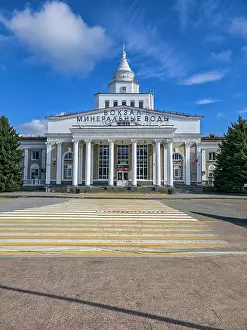 Columns Prints: Historic railway station building in a spa town with blue skies and green trees