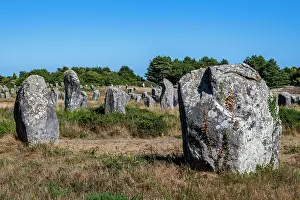 Stones Prints: Historic stone alignment stands under clear blue sky in rural France near ancient ruins and nature