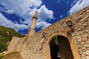 Storytelling Prints: Historic stone fortress wall and Ottoman minaret showcase architecture in Mostar under a vivid sky