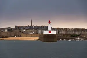 Breakwater Prints: Historic walled city of Saint-Malo with red and white lighthouse on breakwater in Brittany France during twilight