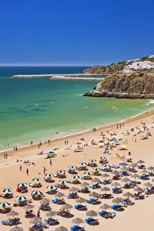 Beach Umbrella Prints: Holidaymakers sunbathing under beach umbrellas on the sandy beach at Praia do Tunel