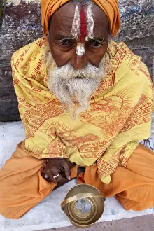 Orange Colour Prints: Holy man begging outside a temple, Vrindavan, Uttar Pradesh, India, Asia