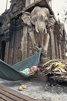 Hammock Prints: Homeless woman in a hammock attached to an elephant carving in a central temple in Phnom Penh