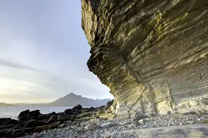 Honeycombe Rock bathed in evening light with Cuillin Hills in distance