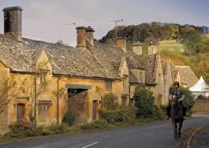 Rider Prints: Horse and rider passing honey coloured stone cottages in the village of Stanton