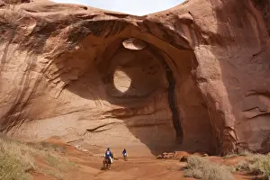 Tribal Park Prints: Horse riding trip, tourist with Navajo guide pass under rock arch