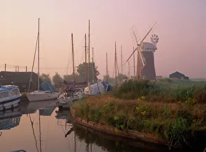 Horsey Wind Pump and boats moored on the Norfolk Broads at dawn, Norfolk