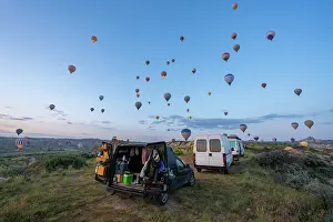 Love Prints: Hot air balloons rise over camper vans at sunrise in Love valley in Cappadocia, Turkey