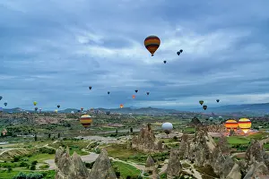 Cappadocia Prints: Hot air balloons rise in Cappadocia as the sun begins to light the sky over the valleys and rock formations