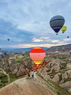 Cappadocia Prints: Hot air balloons rise over Cappadocia as tourists watch during sunrise in Goreme, Turkey