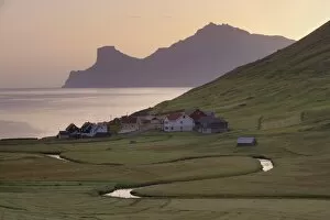 Houses at Elduvik at sunrise, with view across Funningsfjordur of Kalsoy cliffs of Nestindar