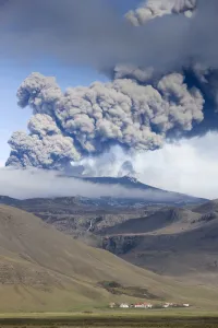 Eruption Prints: Houses at foot of mountains with the ash plume of the Eyjafjallajokull eruption in the distance