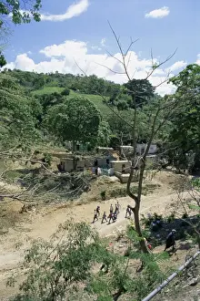 Haiti Prints: Houses and people walking in dry river bed caused by erosion