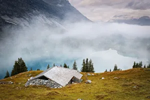 Bern Canton Prints: Hut on mountain ridge above lake Oeschinensee covered by mist, Bernese Oberland