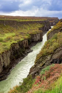 Columns Prints: Hvit River flows through canyon with basalt columns and green vegetation in Iceland
