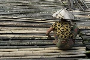 Toiling Collection: Iban tribeswoman mending bamboo longhouse verandah floor, Lemanak River