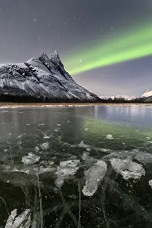 Polar Aurorae Prints: Ice bubbles of frozen sea and the snowy peak of Otertinden under the Northern Lights