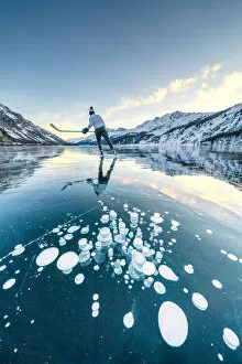 Search Results: Ice hockey player skating on frozen Lake Sils covered of bubbles, Engadine