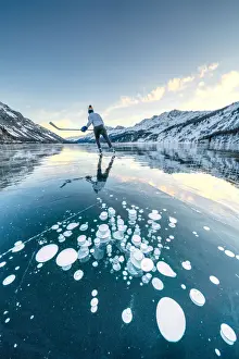 Adults Prints: Ice hockey player skating on frozen Lake Sils covered of bubbles, Engadine