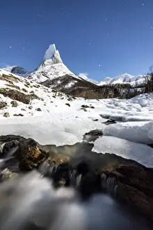 Starry Sky Prints: Ice on rocks frames the granitic snowy peak of the Stetind mountain under the starry sky