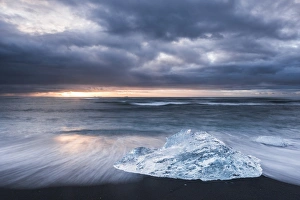 Iceberg at sunrise on Jokulsarlon Beach, a black volcanic sand beach in South East Iceland
