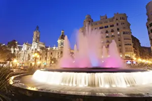 Illuminated fountain on Plaza del Ayuntamineto with town hall at dusk, Valencia, Comunidad Valencia, Spain, Europe