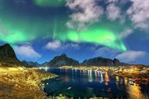 Reine Prints: Illuminated harbor of Reine under the bright green lights of the Aurora Borealis (Northern Lights)