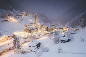 Valtellina Prints: Illuminated village of Gerola Alta and frozen river covered with snow during winter dusk