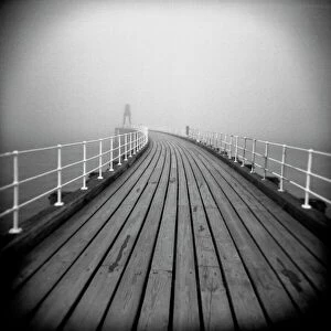 Monochrome Gallery: Image taken with a Holga medium format 120 film toy camera looking along timber boardwalk of Whitby pier on misty winters day