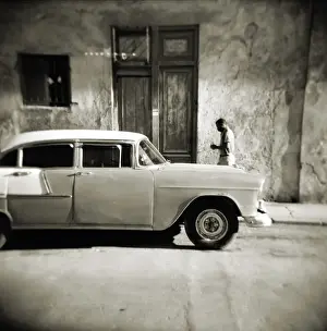 Image taken with a Holga medium format 120 film toy camera of man walking past old American car