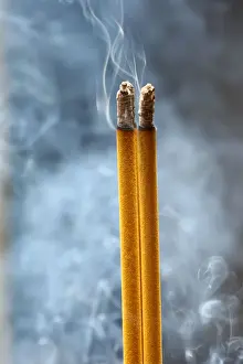 Foreground Focus Prints: Incense sticks on joss stick pot burning and smoke used to pay respect to Buddha