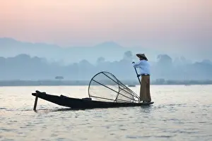 Intha leg rowing fishermen at dawn on Inle Lake who row traditional wooden boats using their leg and fish using nets stretched over conical bamboo frames, Inle Lake, Myanmar (Burma), Southeast Asia