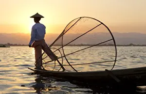Intha leg rowing fishermen at sunset on Inle Lake who row traditional wooden boats using their leg and fish using nets stretched over conical bamboo frames, Inle Lake, Myanmar (Burma), Southeast Asia