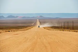 A jeep on a long sandy road in southern Namibia leaves a trail of dust, Namibia, Africa