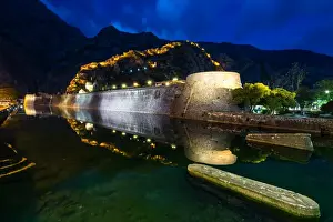 Montenegro Prints: Part of Kotors old town wall and lit fortress ramparts reflected during the evening blue hour