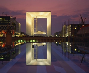 La Defense Prints: La Grande Arche illuminated at dusk, seen from across the ornamental lake