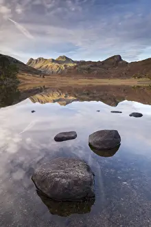 The Langdale Pikes mountains reflected in the mirror still water of Blea Tarn in autumn
