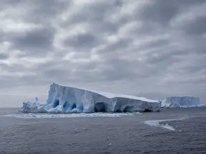 Antarctica Prints: A large iceberg with holes and arches formed in it near Coronation Island