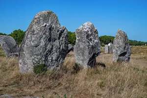 Stones Prints: Large standing stones are arranged in a rocky field under a clear blue sky in France during daytime