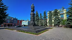 Center Prints: Lenin statue stands in center of Vladikavkaz surrounded by trees and buildings in North Ossetia