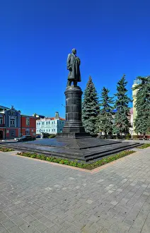Tall Prints: Lenin statue in Vladikavkaz surrounded by buildings and trees on a clear day in North Ossetia