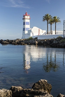 The lighthouse reflected in the blue water under the blue summer sky, Cascais, Estoril Coast