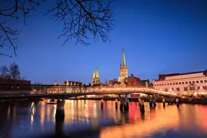 River Trave Prints: The lights of dusk on typical bridge and the cathedral reflected in River Trave, Lubeck