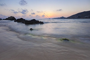 The last lights of the sunset are reflected on sea waves and sandy beach, Licata